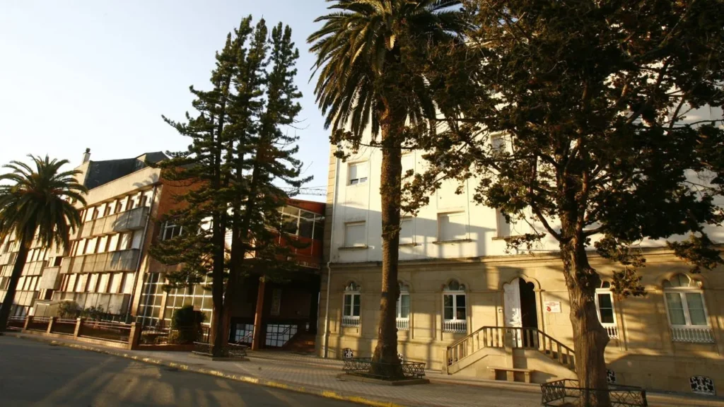 sagrado epic Imaxe do colexio Sagrado Corazón vista desde abaixo, enfoca na parte de secretaria con 3 árbores enfrente e o outro edificio ao carón